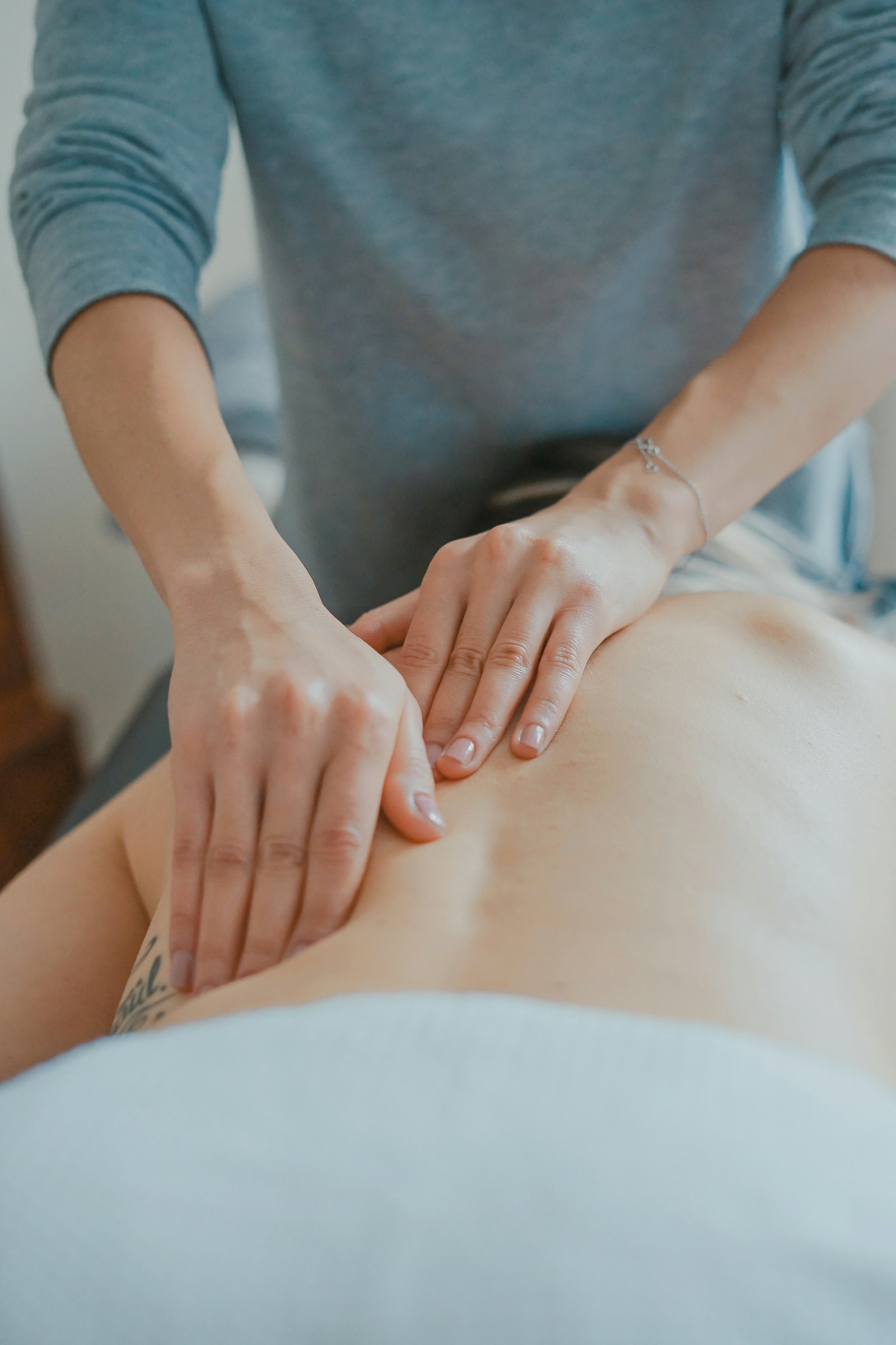 A therapist working deeply into a client's back and shoulders